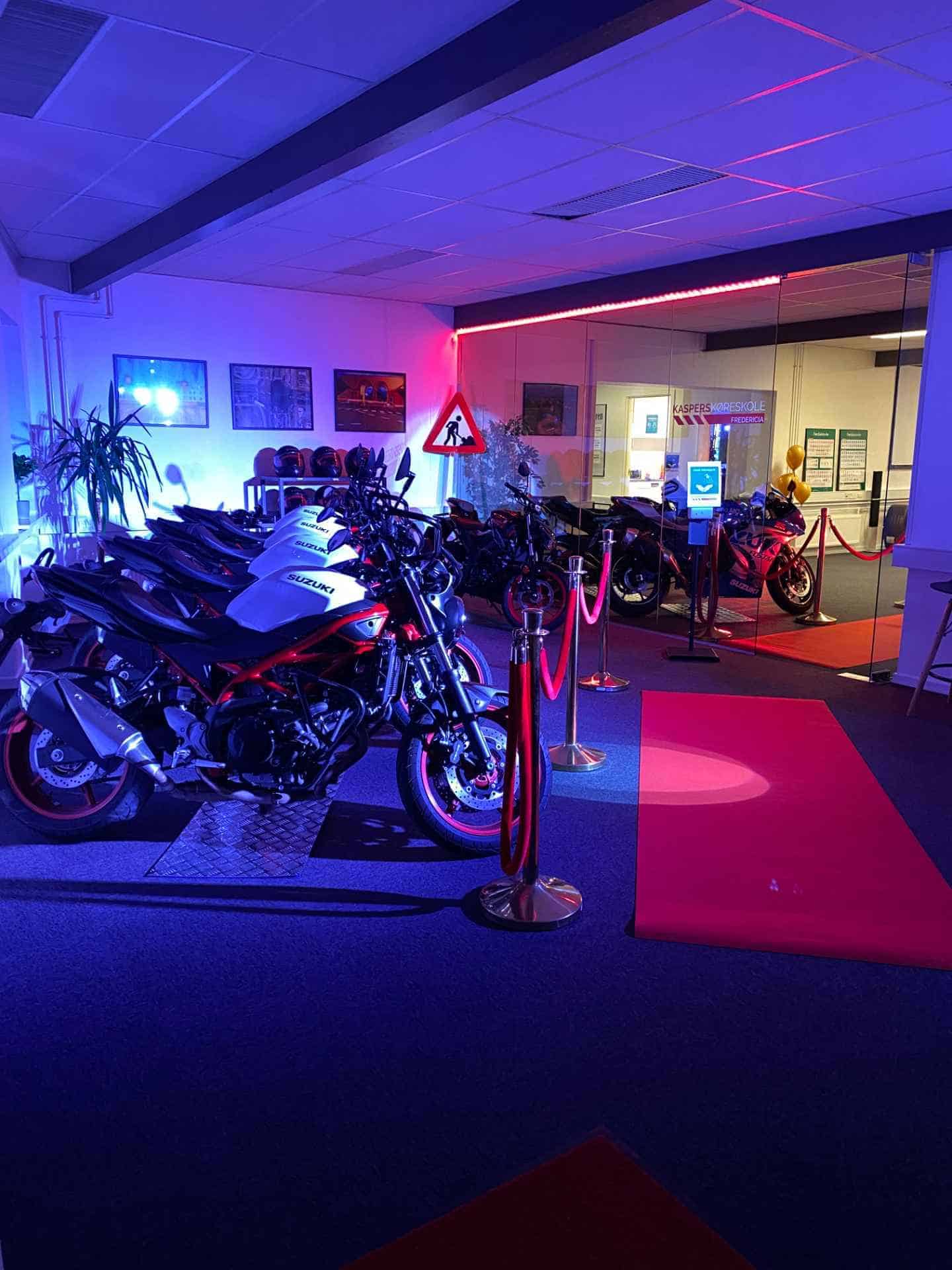 Udstillingslokale med motorcykler oplyst af lilla neonlys