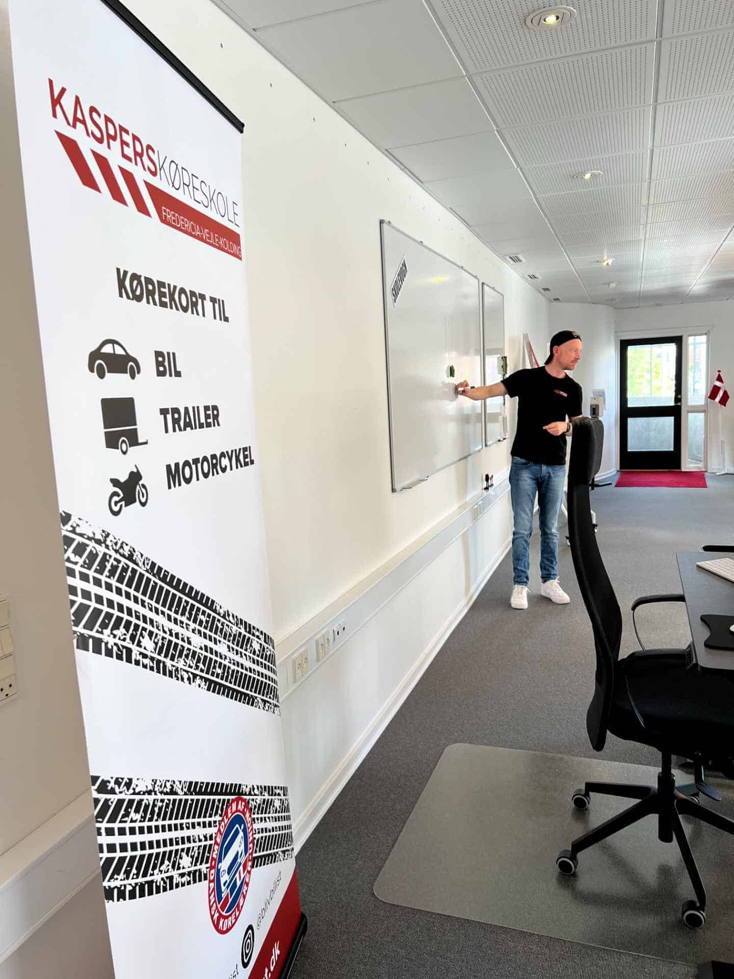 Kørelærer gennemgår regler på whiteboard i teorilokalet
